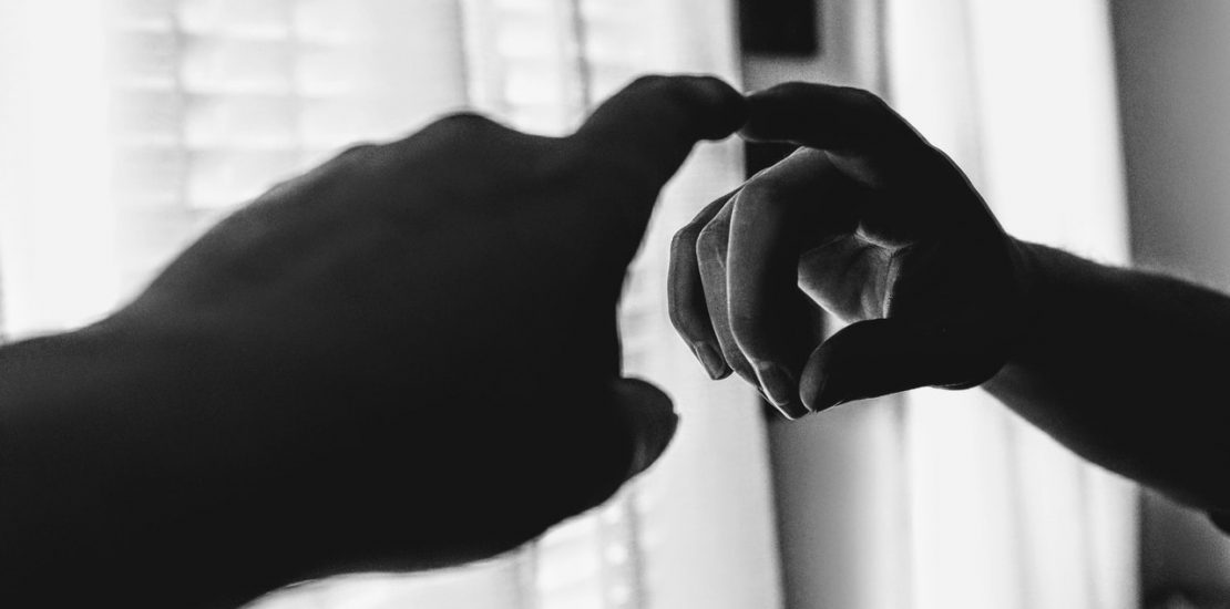 A finger pointing at its reflection in a mirror.